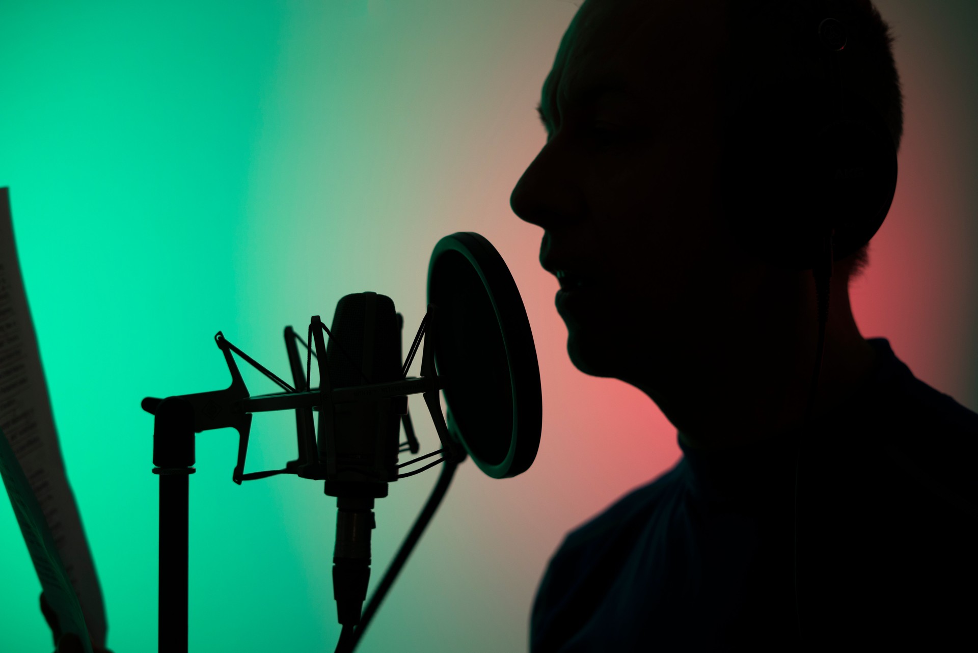 Voiceover artist voice actor in vocal recording studio with larg diaphragm microphone and antipop shield.